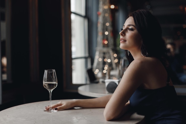 Free photo young pretty woman in dress in cafe with glass of wine