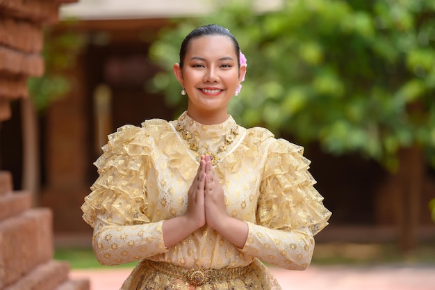 4月のソンクラン祭りタイ新年家族の日に寺院で敬意を表して立っている美しいタイの衣装を着た若いきれいな女性