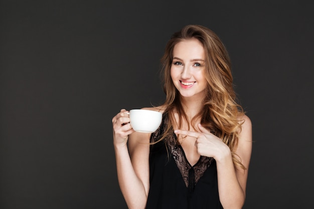 Young pretty woman drinking coffee and pointing