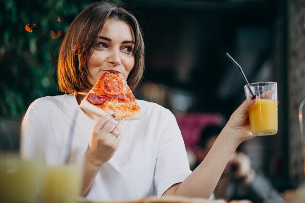 Young pretty woman eating pizza at a bar
