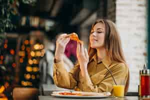 Free photo young pretty woman eating pizza at a bar