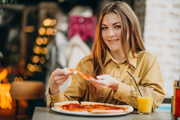 Young pretty woman eating pizza at a bar