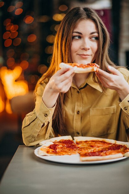 Young pretty woman eating pizza at a bar