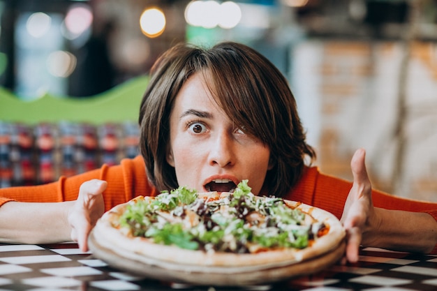 Free photo young pretty woman eating pizza at pizza bar