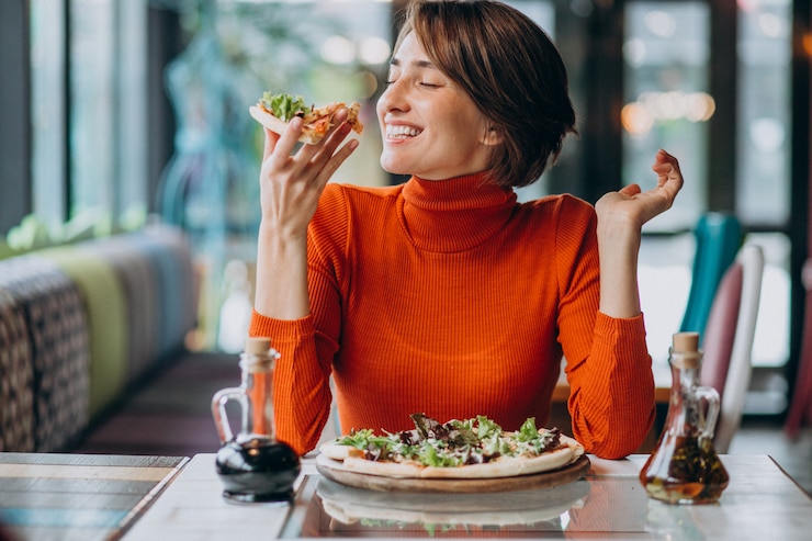 Free Photo young pretty woman eating pizza at pizza bar