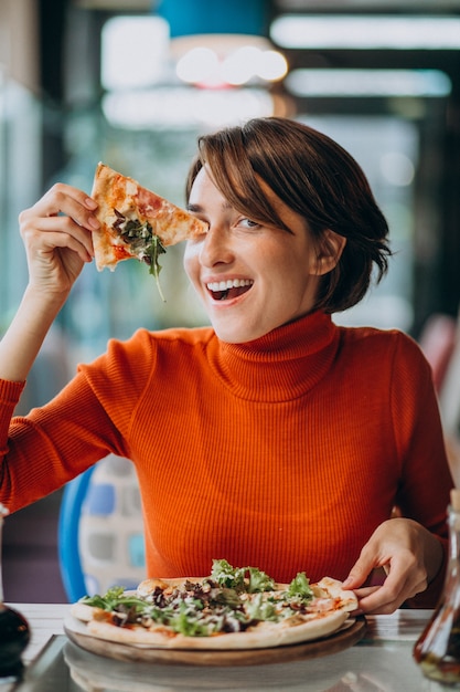 Young pretty woman eating pizza at pizza bar