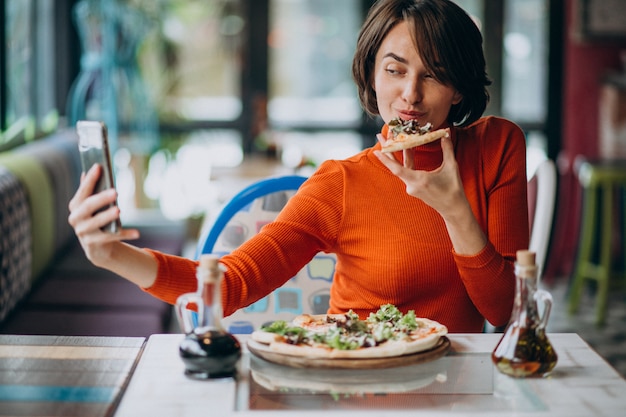 Young pretty woman eating pizza at pizza bar