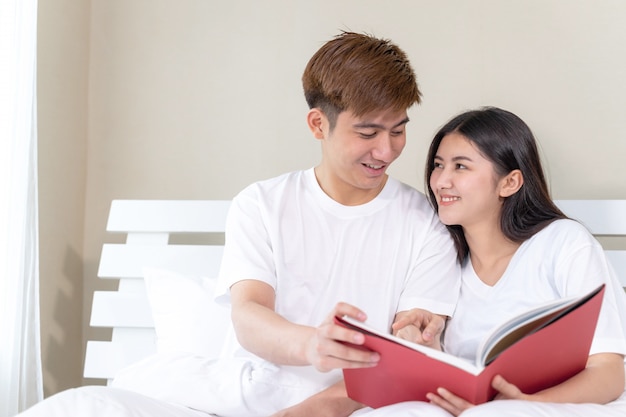 Молодая красивая женщина и красивый парень, чтение книг на кровати у себя дома