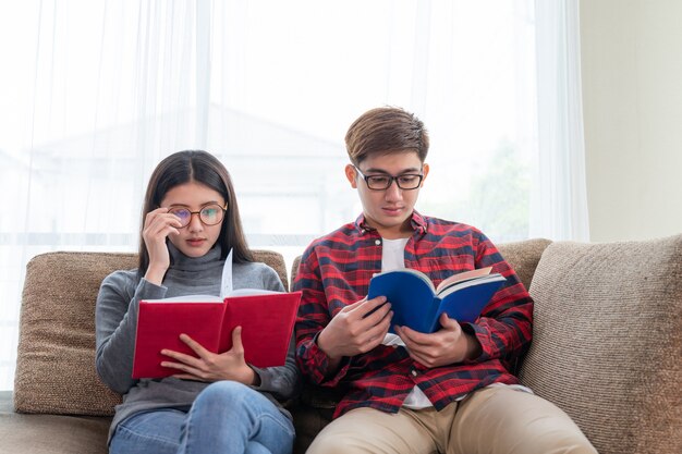 Young pretty woman and handsome man reading on sofa