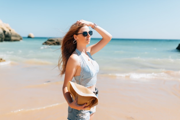 Молодая красивая женщина в шляпе на пляже в океане