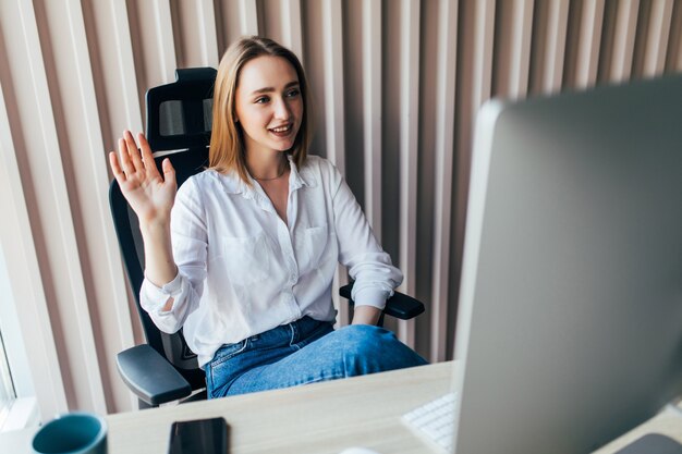 Young pretty woman having video call via laptop in the office