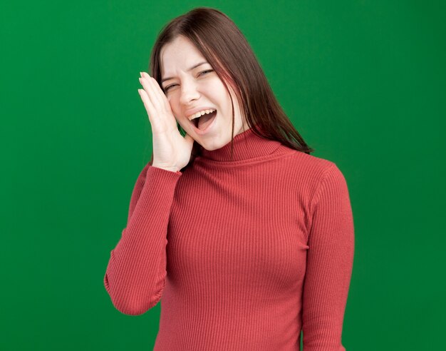 Young pretty woman keeping hand near mouth calling out loud to someone