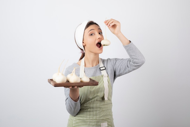 young pretty woman model in apron eating a white radish.