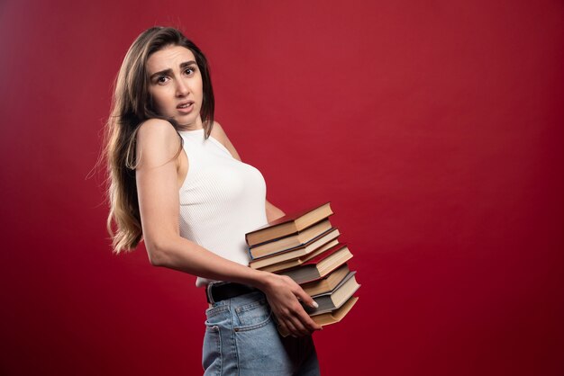 Young pretty woman model carrying a lot of books 