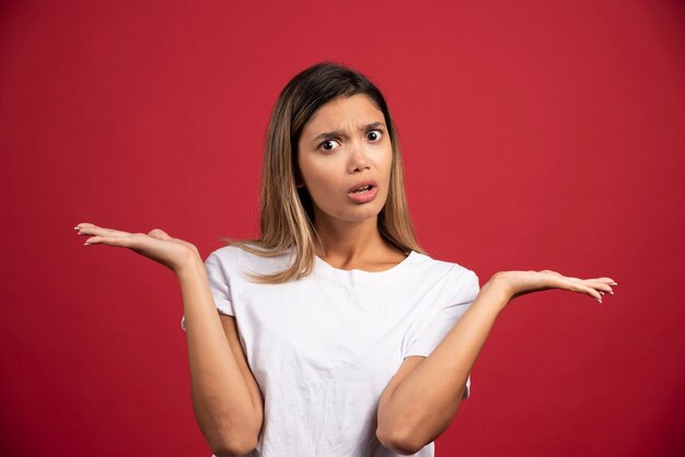 Young pretty woman posing on red wall.