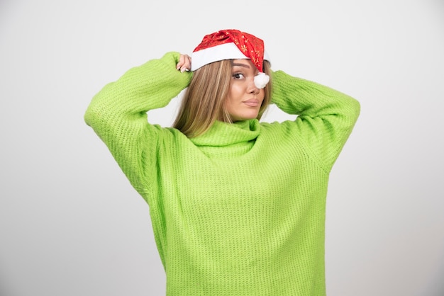 Молодая красивая женщина позирует в красной шляпе Санта-Клауса.