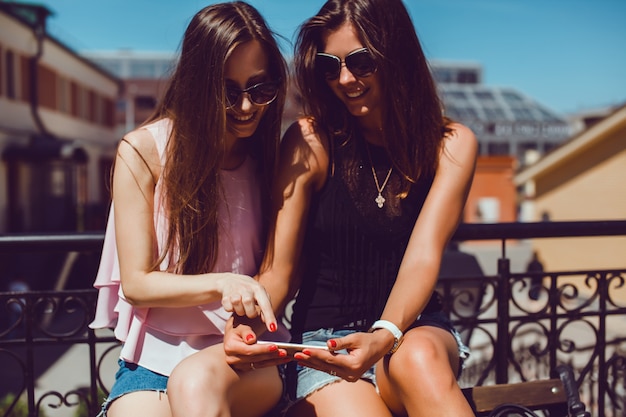 Foto gratuita giovane donna graziosa che presentano in strada con il telefono