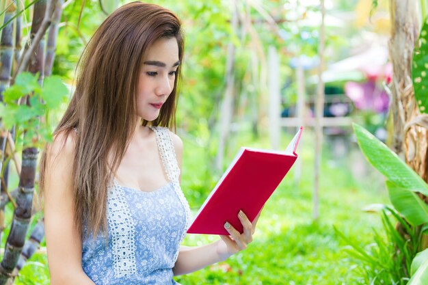 Young pretty woman reading book in park