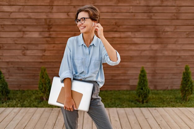 Young pretty woman sitting with laptop in modern park street