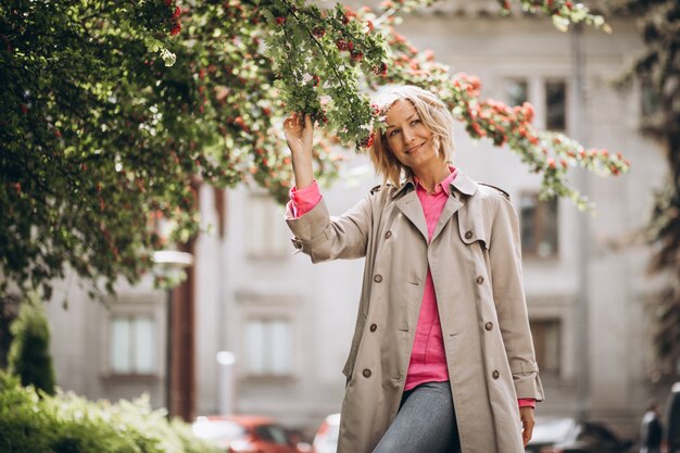 Young pretty woman standing by the flowers in park