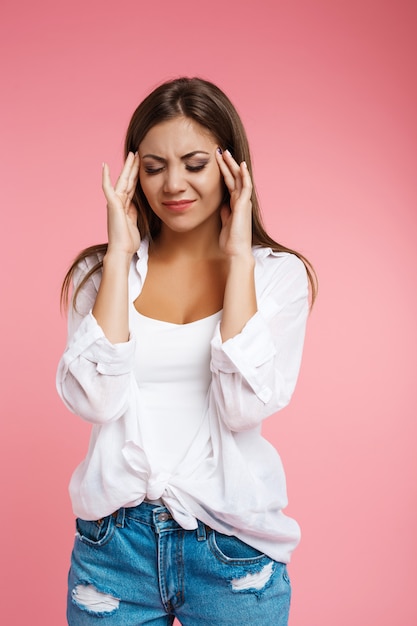 Foto gratuita giovane donna graziosa che soffre di terribile mal di testa tenendo la testa