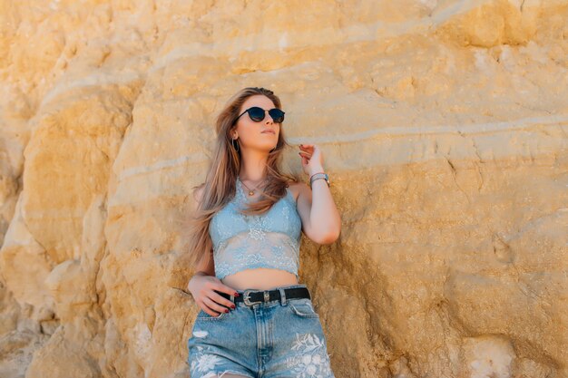 Young pretty woman in sunglasses on the rocky beach