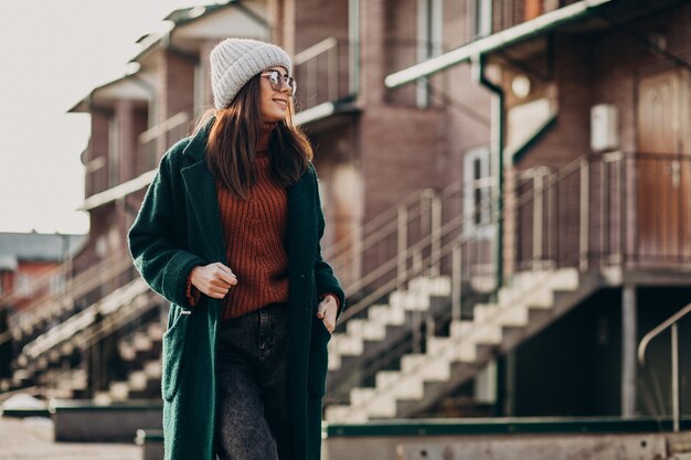 Young pretty woman in warm coat by the house