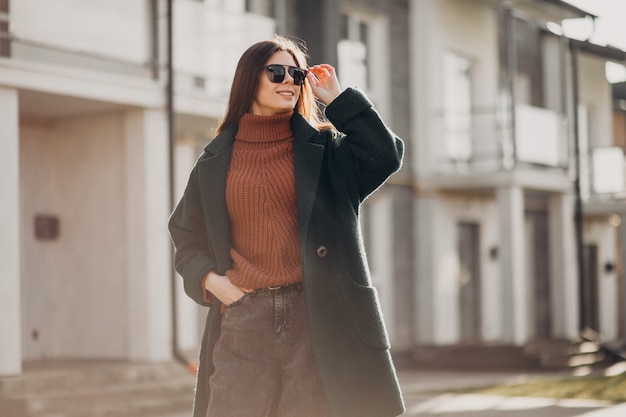 Free photo young pretty woman in warm coat by the house