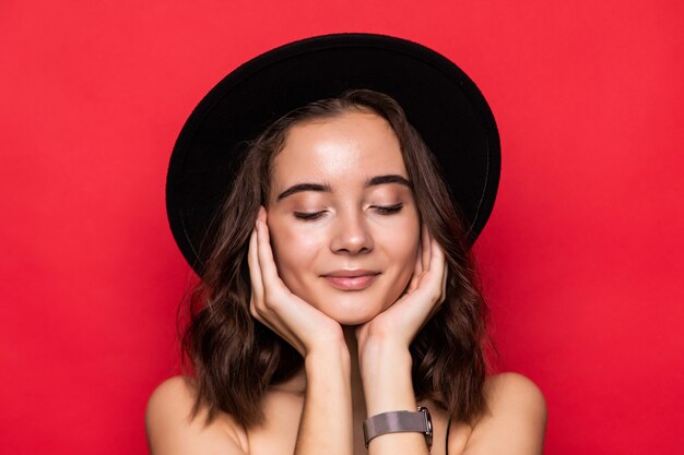 Young pretty woman with floppy hat isolated over red 