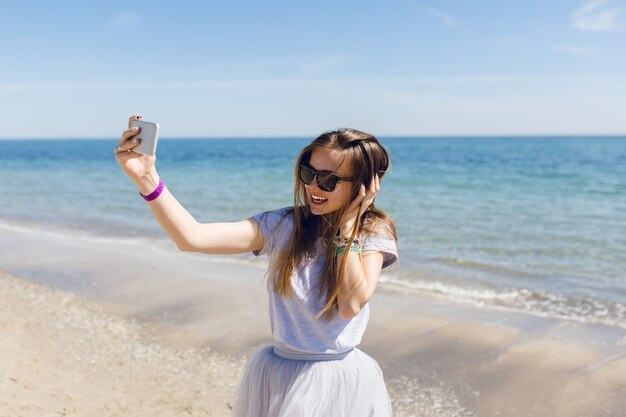 Young pretty woman with long hair is standing near blue sea