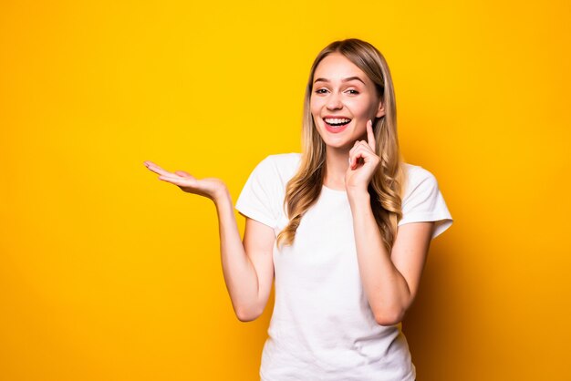 Young pretty woman with open palm isolated on yellow wall