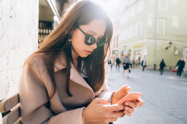 Young pretty woman with smartphone on the city street