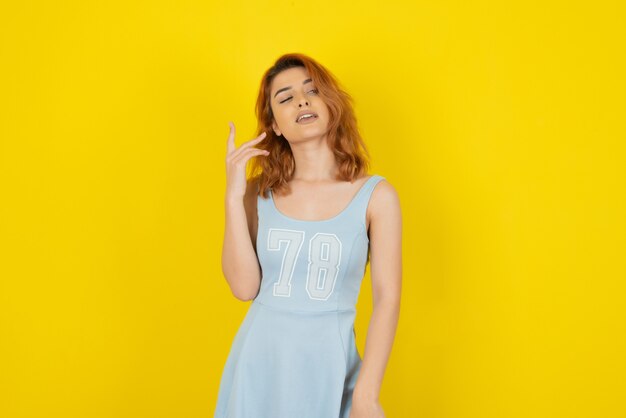Young pretty woman on yellow wall. A confident redhead