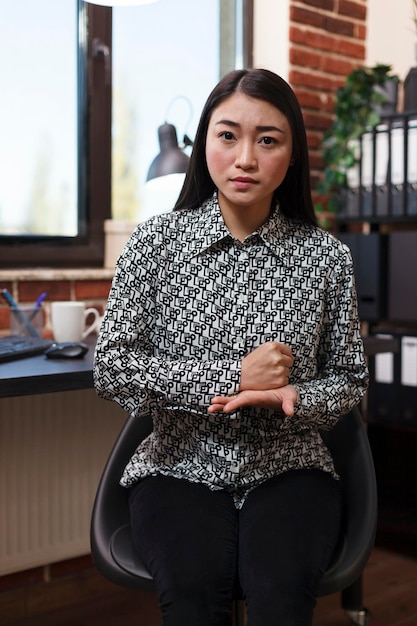 Young productive asian businesswoman explaining urgent business financial matter while making gesture with hands. Marketing company worker looking at camera and hand gesturing.