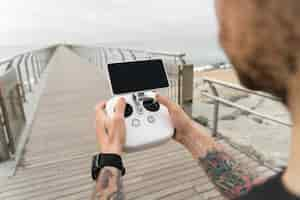 Free photo young professional or amateur photographer or drone pilot holds remote control panel with screen and controls ready to fly quadrocopter in air to see birds point of view.