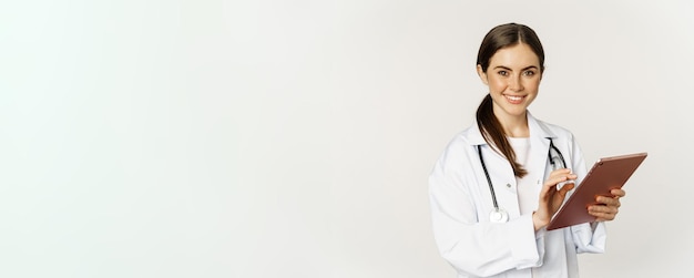 Free photo young professional doctor woman physician with stethoscope holding digital tablet and smiling at cam