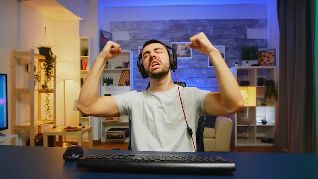 Free photo young professional game player screaming with hands raised after his victory