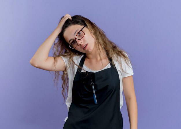 Young professional hairdresser woman in apron confused 