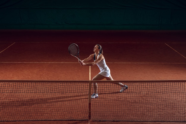 Young professional sportswoman playing tennis on sport court wall