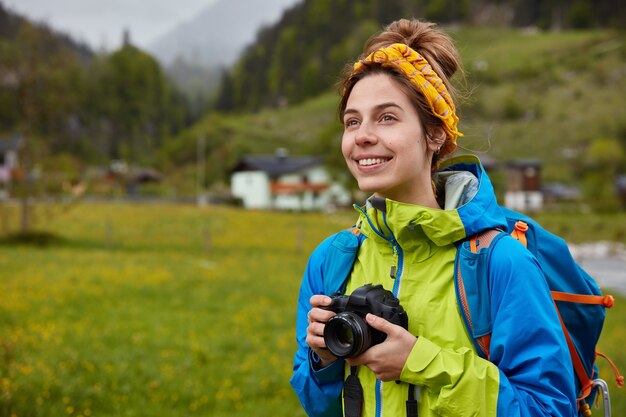 Young professional tourist photographer looks into distance, captures beautiful landscape