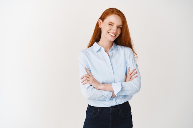 Young professionals Confident redhead woman in blue shirt winking at camera smiling and looking selfassured with arms crossed on chest