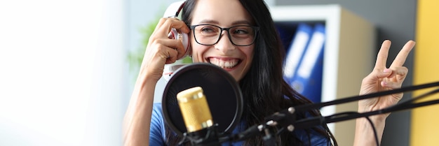 若い​ラジオ​の​司会者​は​スタジオ​で​働き​、​彼女​は​微笑んで​アナウンス​を​生放送​します