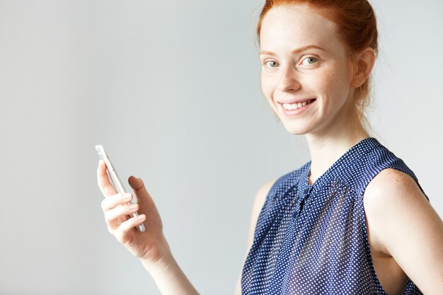 Young red-haired woman holding smartphone