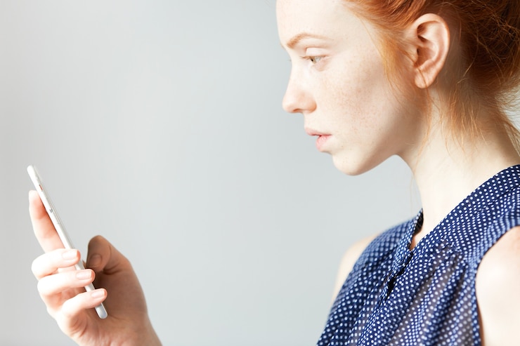 Free Photo young red-haired woman holding smartphone