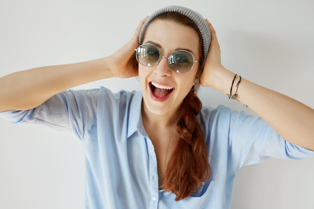 Foto gratuita ragazza giovane rossa che indossa occhiali da sole e cappello