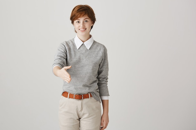 Young redhead girl with short haircut posing against the white wall