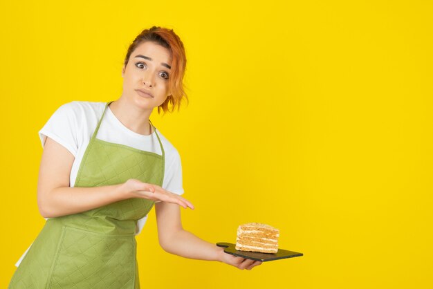 Young redhead seems scared and holding fresh cake slice