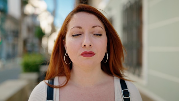 Free photo young redhead woman breathing at street