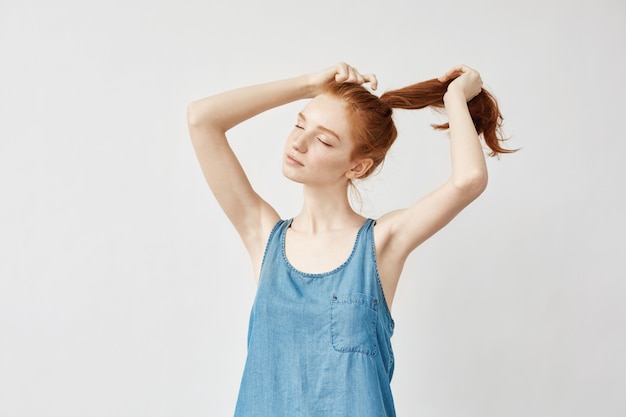 Giovane donna di redhead che corregge il suo taglio di capelli.