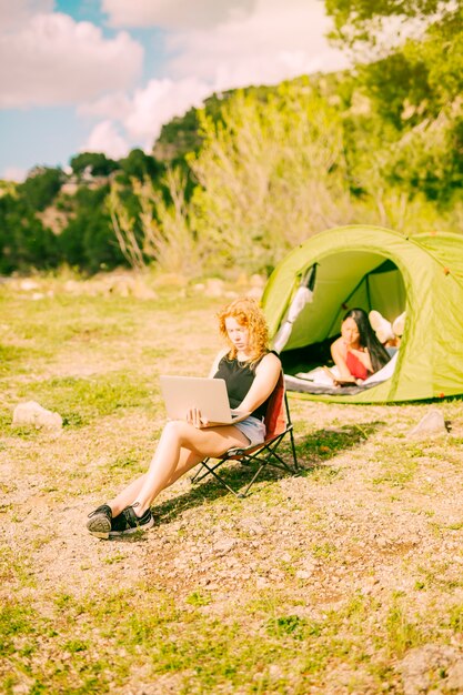 Young redhead woman using laptop on nature